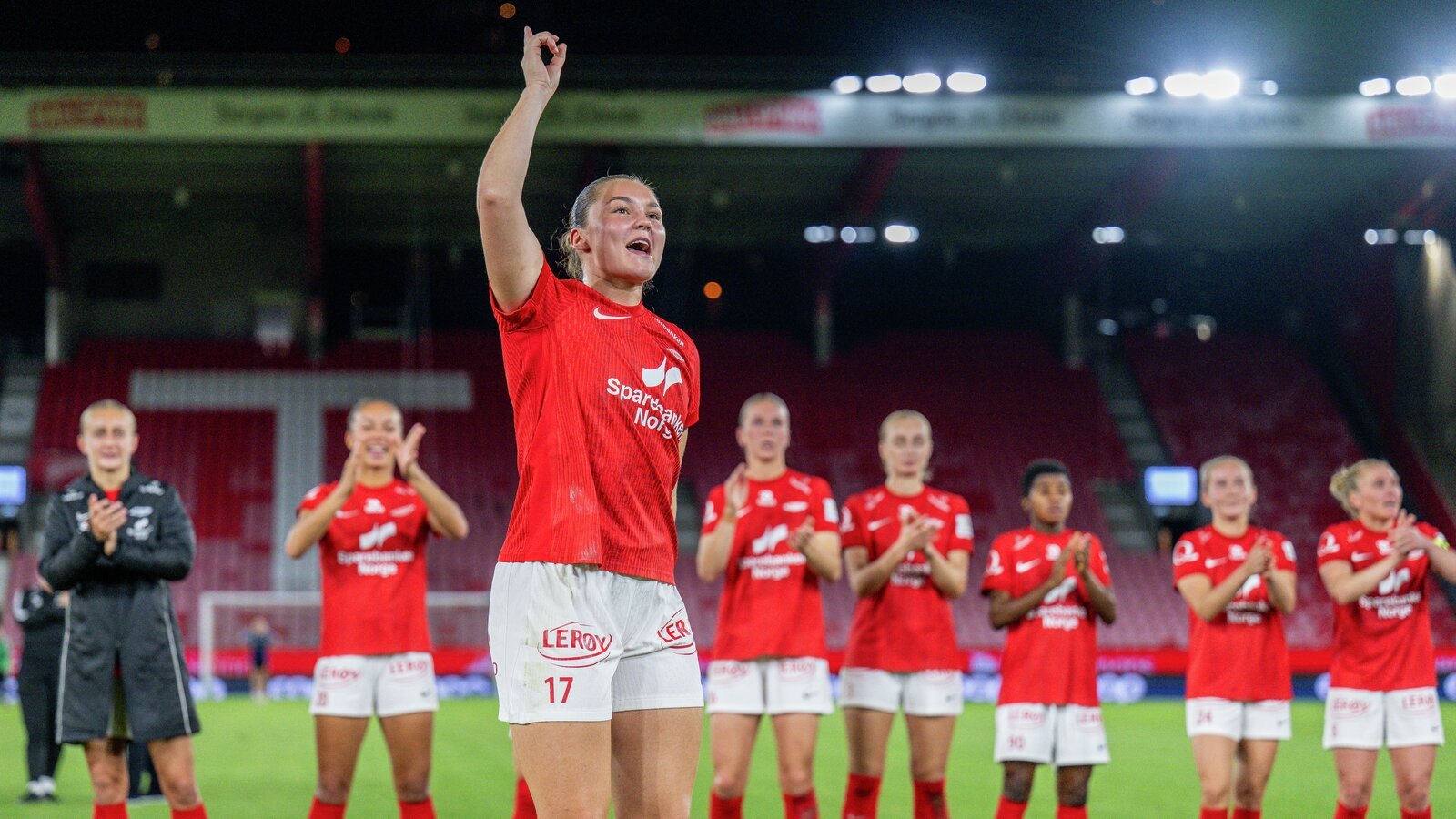 En rugbyspiller i rød trøye feirer med lagkamerater på banen etter en kamp.